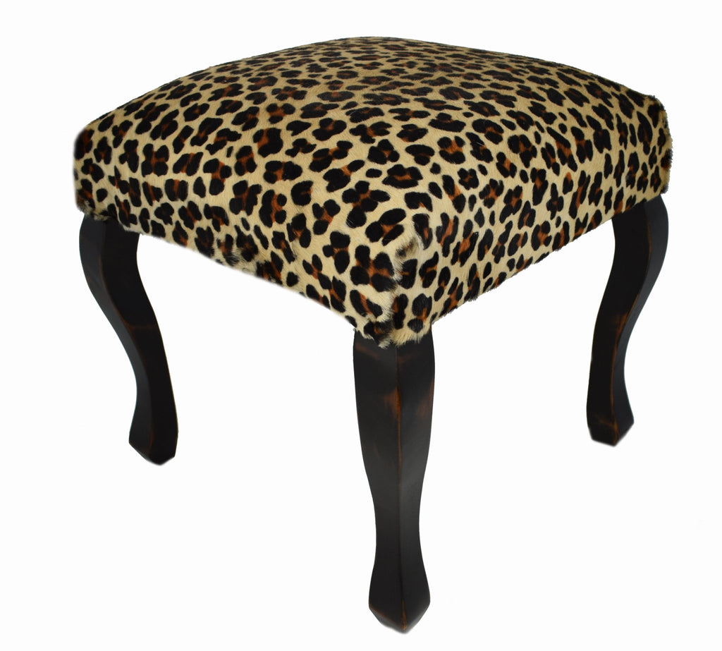 Accentuate your wild side with our Leopard Printed Cowhide Upholstered Stool. Upholstered here in the USA, every piece begins with a decorative wood frame featuring beautifully sculpted legs, finished in our expresso coffee color, then upholstered with a beige cowhide that has been printed with a leopard print.  Size is 18” square. 